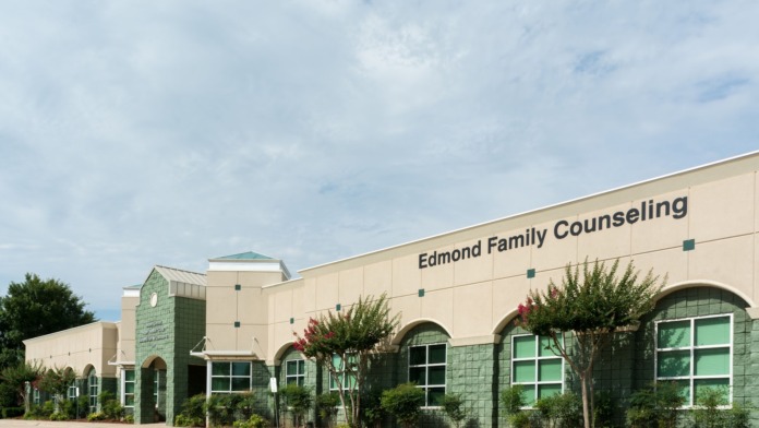 Exterior entrance view showing green tiled facade, arched doorway, windows, and flowering shrubs