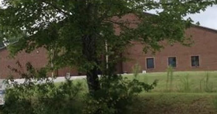 Exterior of brick treatment facility with entrance area, lawn, and surrounding trees visible from the property