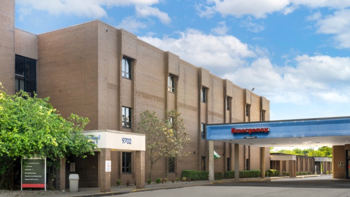 Exterior view of multi-story brick facility with windows, landscaping, and professional grounds design