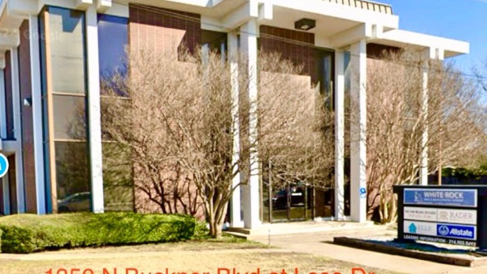 Exterior view of modern treatment facility with white columns, large windows, landscaped grounds, and entrance signage