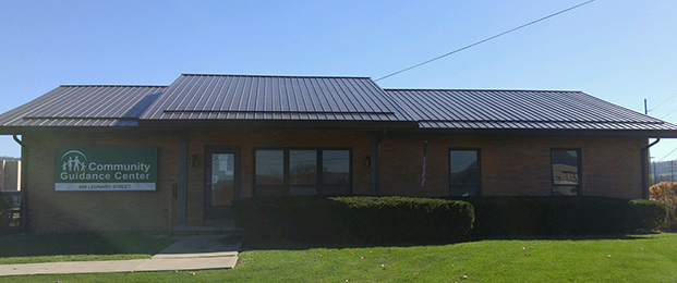 Exterior view of brick treatment center building with landscaped lawn area and metal roof