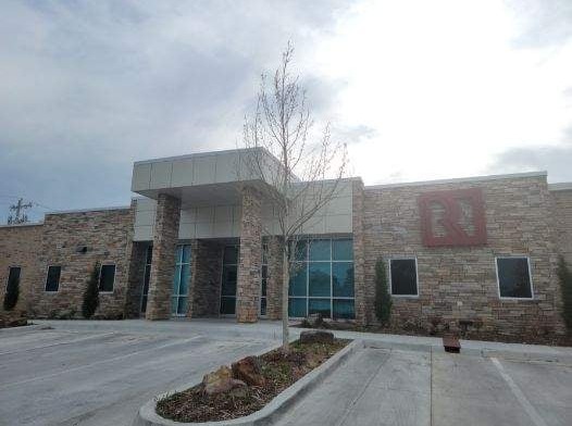 Exterior view showing stone and metal facade of treatment facility with red roof, large windows, and front parking lot