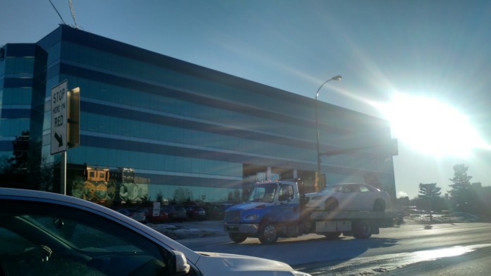 Exterior side view of clinic building showing glass windows, service vehicle, parking area, and surrounding landscaping