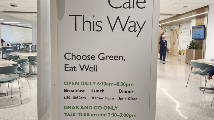 Interior signage for Suburban Cafe with hours and menu offerings, adjacent to seating area and kitchen service area
