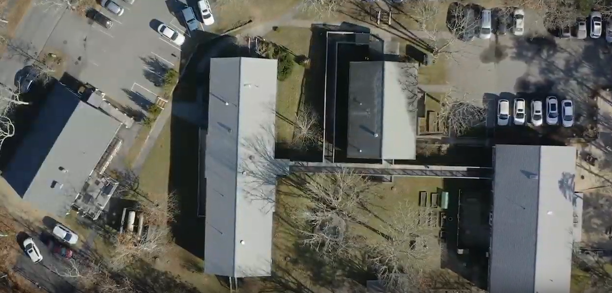 Aerial view of facility campus showing multiple buildings, parking areas, and landscaped grounds layout