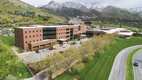 Distant aerial view of modern treatment facility complex with mountains, parking, and manicured grounds