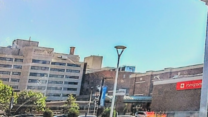 Outdoor courtyard with landscaped grounds, pathways, benches, and modern healthcare facility building