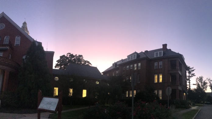 Exterior evening view of brick buildings with illuminated windows and manicured grounds