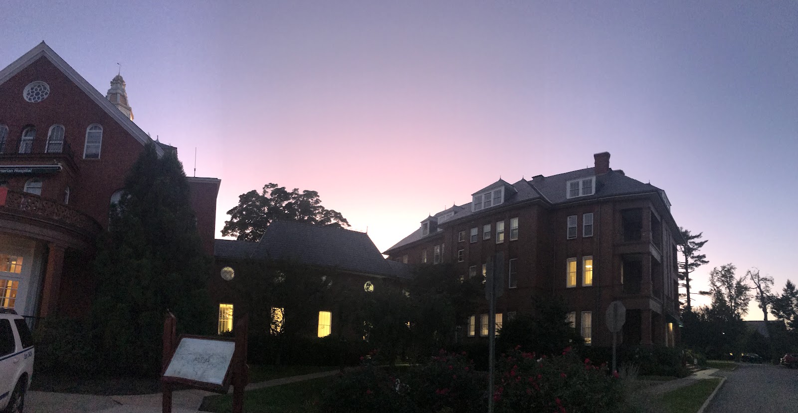 Exterior evening view of brick buildings with illuminated windows and manicured grounds
