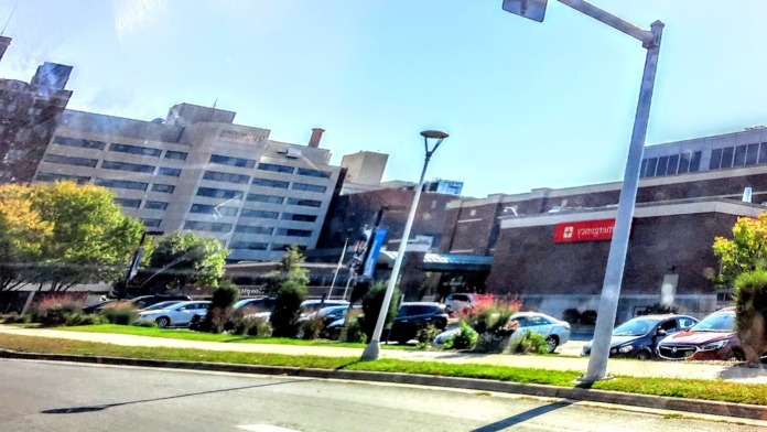 Exterior view of campus grounds with multiple healthcare buildings, parking areas, landscaping and pathways