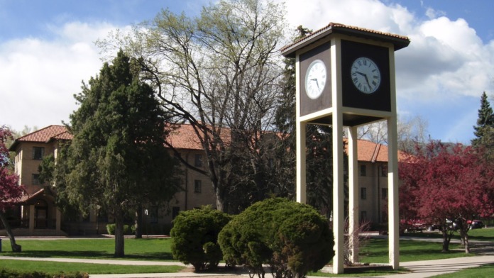 Exterior view of facility grounds featuring distinctive clock tower, manicured lawn, and landscaped pathways with trees