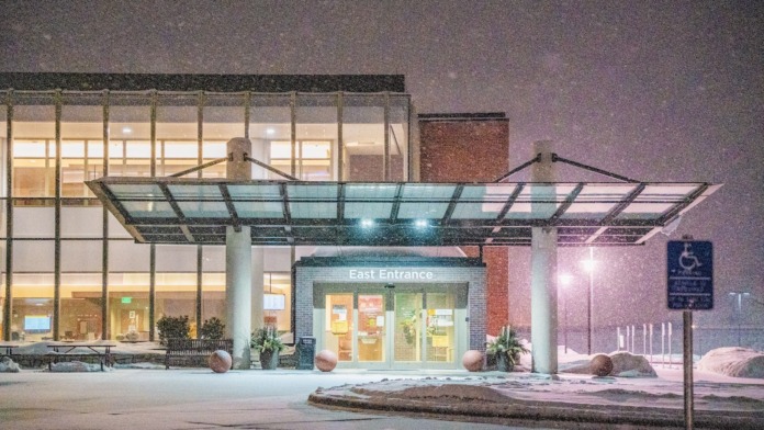 Exterior facility view with falling snow, illuminated entrance, architectural features, and modern healthcare building design