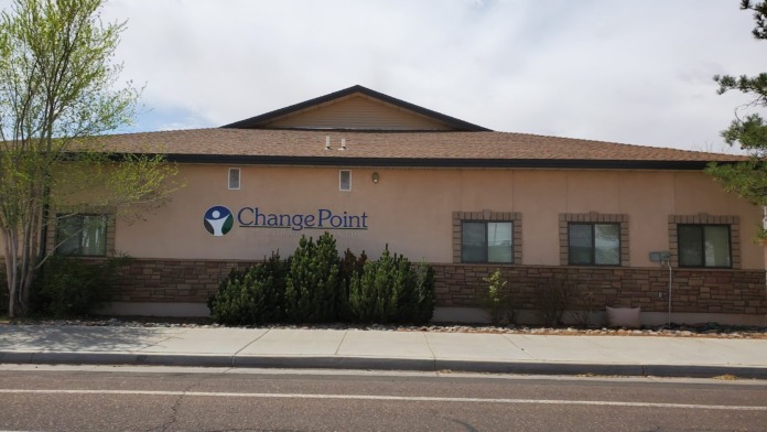 Exterior view of ChangePoint Integrated Health facility showing tan stucco building with brick base, facility signage, windows, and landscaping