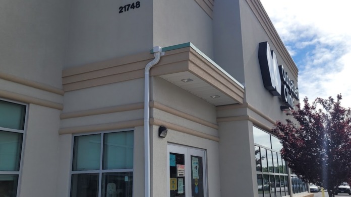 Exterior close-up of clinic entrance with address number and glass doors, showing architectural details and landscaping