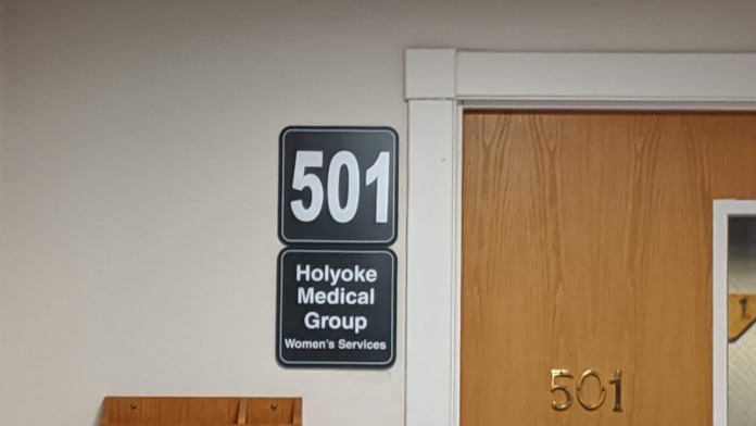 Interior hallway with directional signage, restroom access, and wayfinding for laboratory waiting and medical services