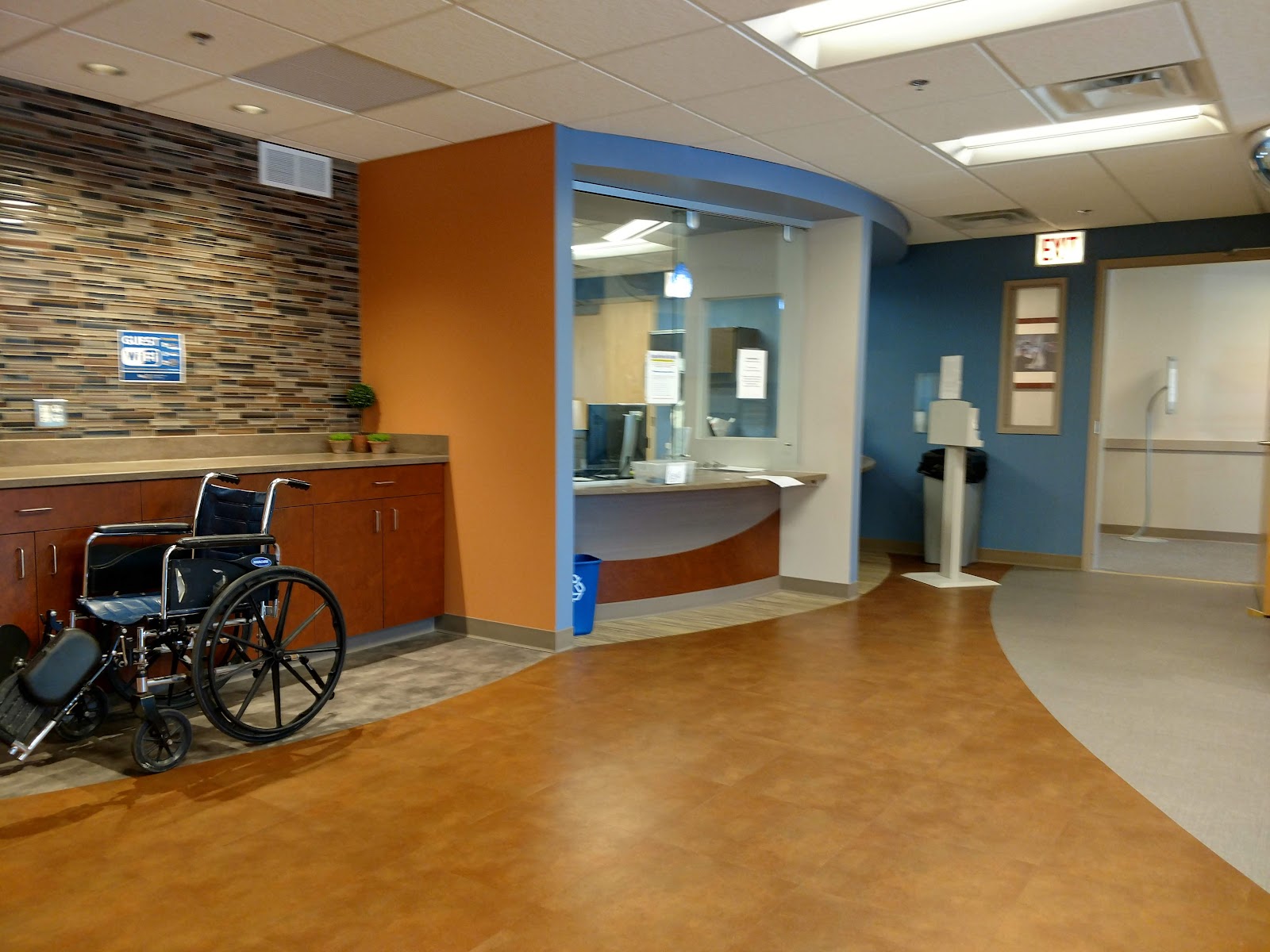 Interior clinical space with reception desk, colorful accent walls in orange and blue, modern flooring and furniture