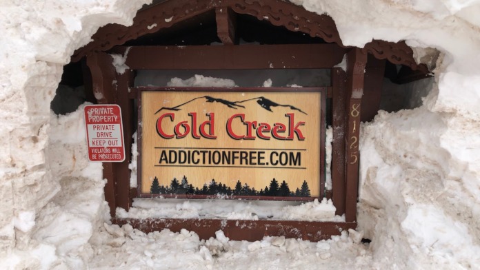 Exterior entrance sign for Cold Creek sober living facility mounted on snow-covered structure with private property notice