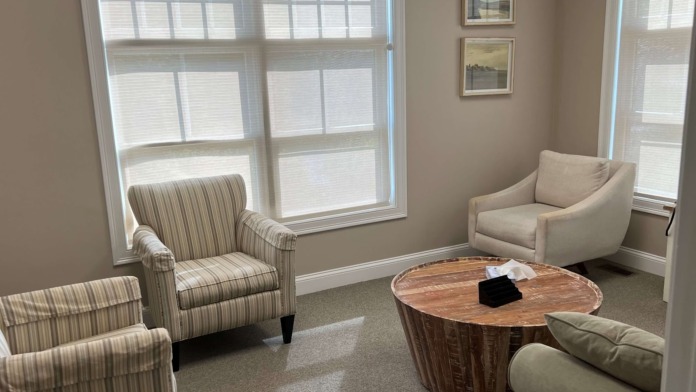 Interior lounge with armchairs, wooden side tables, wall-mounted mirrors, and television area