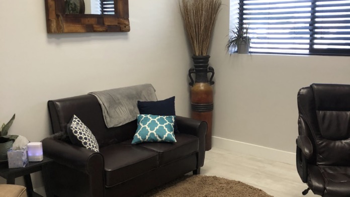 Interior space with black leather sofas, round area rug, framed landscape art, decorative mirror, and window treatments.