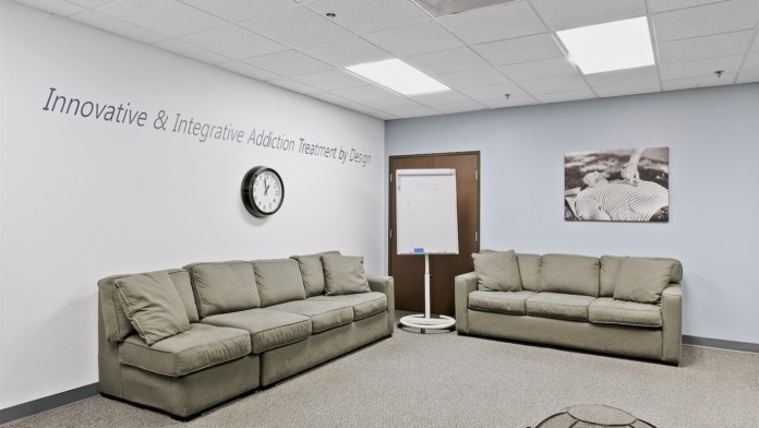 Interior common lounge area with two beige couches, clock, wall signage, and treatment photography