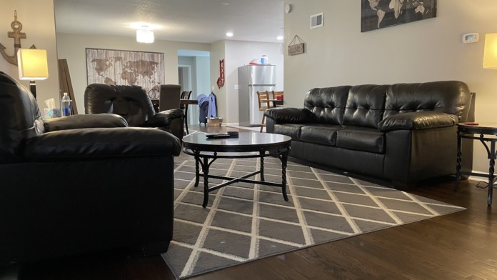 Interior common room with black leather sofas, round coffee table, wooden décor, and wall art including world map