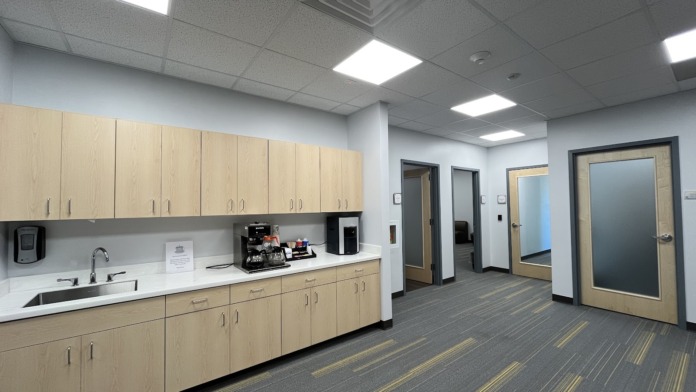 Interior kitchen facility with wooden cabinetry, sink, countertops, appliances, and dining area with tables