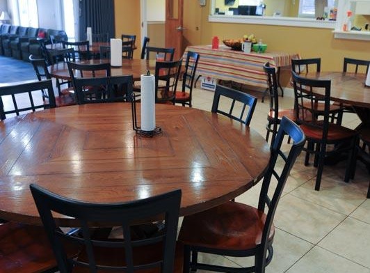 Interior dining space with round table seating, chairs, check-in counter, and lounge seating area with warm lighting