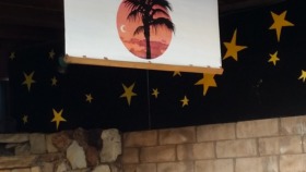 Interior event space featuring wooden stage with welcome signage for comedy night and decorative star backdrop