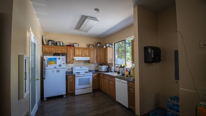 Interior kitchen with wooden cabinetry, stainless steel appliances, and windows overlooking grounds