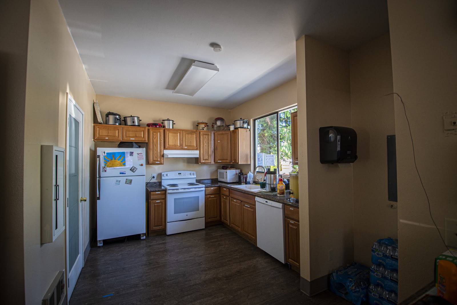 Interior kitchen with wooden cabinetry, stainless steel appliances, and windows overlooking grounds