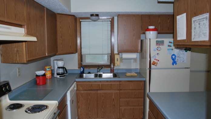 Interior kitchen with wood cabinetry, stainless steel appliances, countertops, and window with blinds