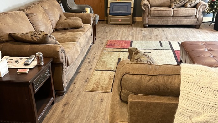 Interior living area with multiple upholstered couches, armchairs, wood accents, decorative wall art, and entertainment setup
