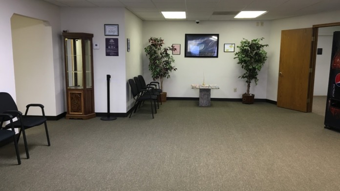 Interior reception lobby with seating chairs, plants, television, bulletin boards, and doors leading to facility spaces