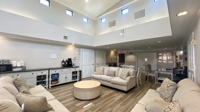 Interior community lounge with multiple seating arrangements, high ceilings, and natural lighting from skylights