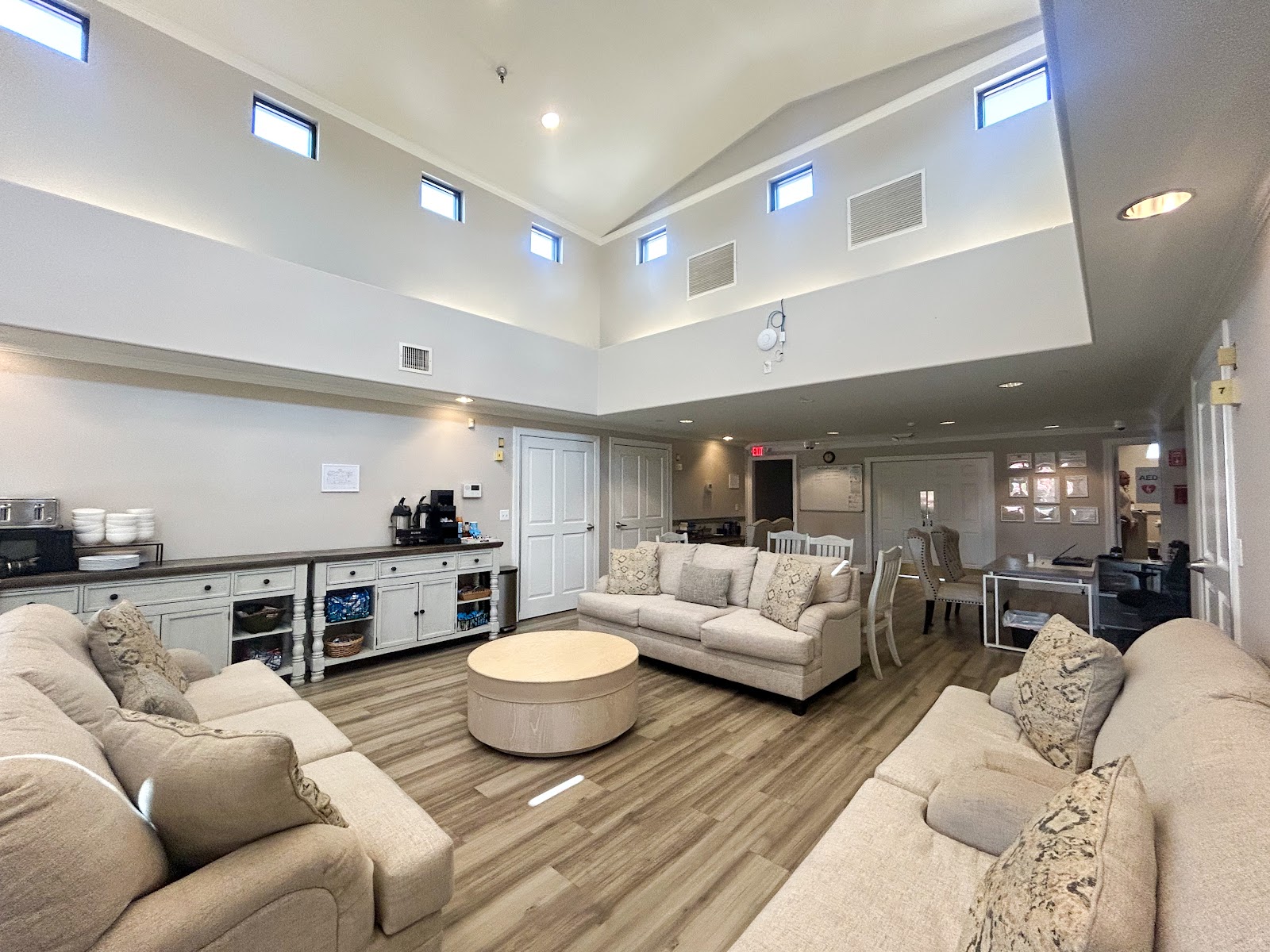 Interior community lounge with multiple seating arrangements, high ceilings, and natural lighting from skylights