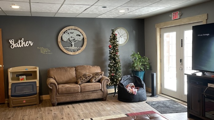Interior community lounge with comfortable seating, brown leather sofas, decorative wall art, television, and casual gathering area