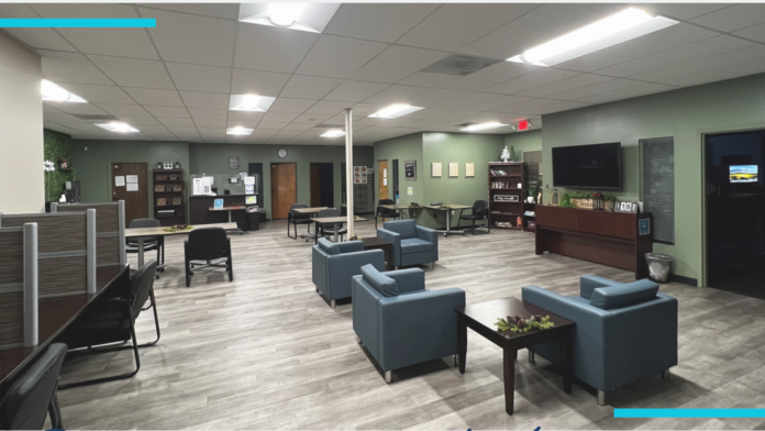 Interior community lounge with seating areas, reception desk, television, and administrative spaces in modern treatment facility