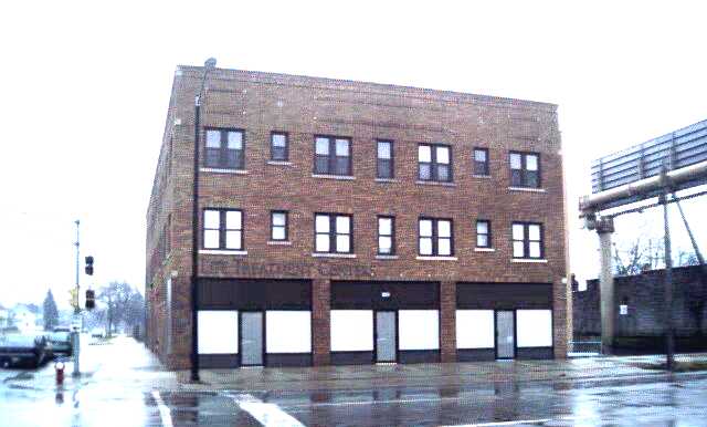 Exterior corner view of brick treatment facility building with multiple windows on wet pavement