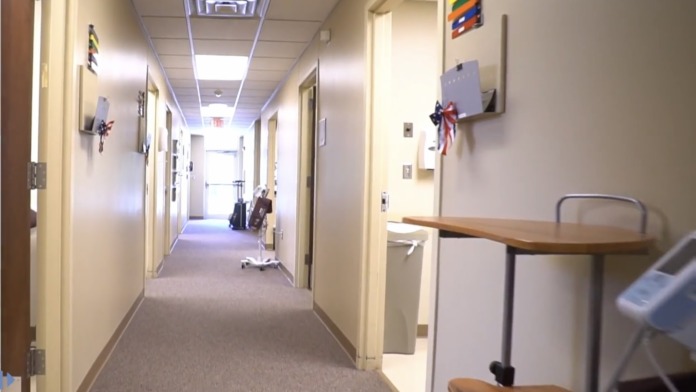 Interior hallway with doorways to examination rooms, emergency exit sign, and clerestory ceiling lighting