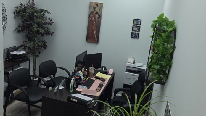 Interior administrative office with desk, computer, black chairs, plants, and professional décor under fluorescent lighting