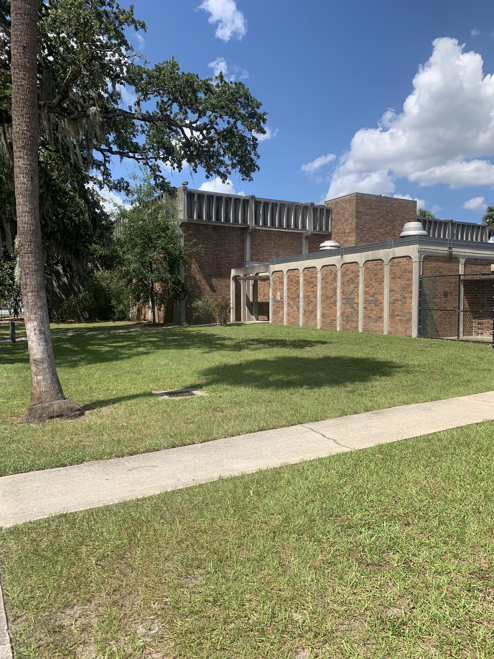 Exterior view showing brick building with covered pavilion structure and manicured lawn space