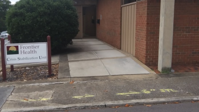Exterior view of brick Crisis Stabilization Unit building with concrete walkway, entrance door, and facility identifier sign