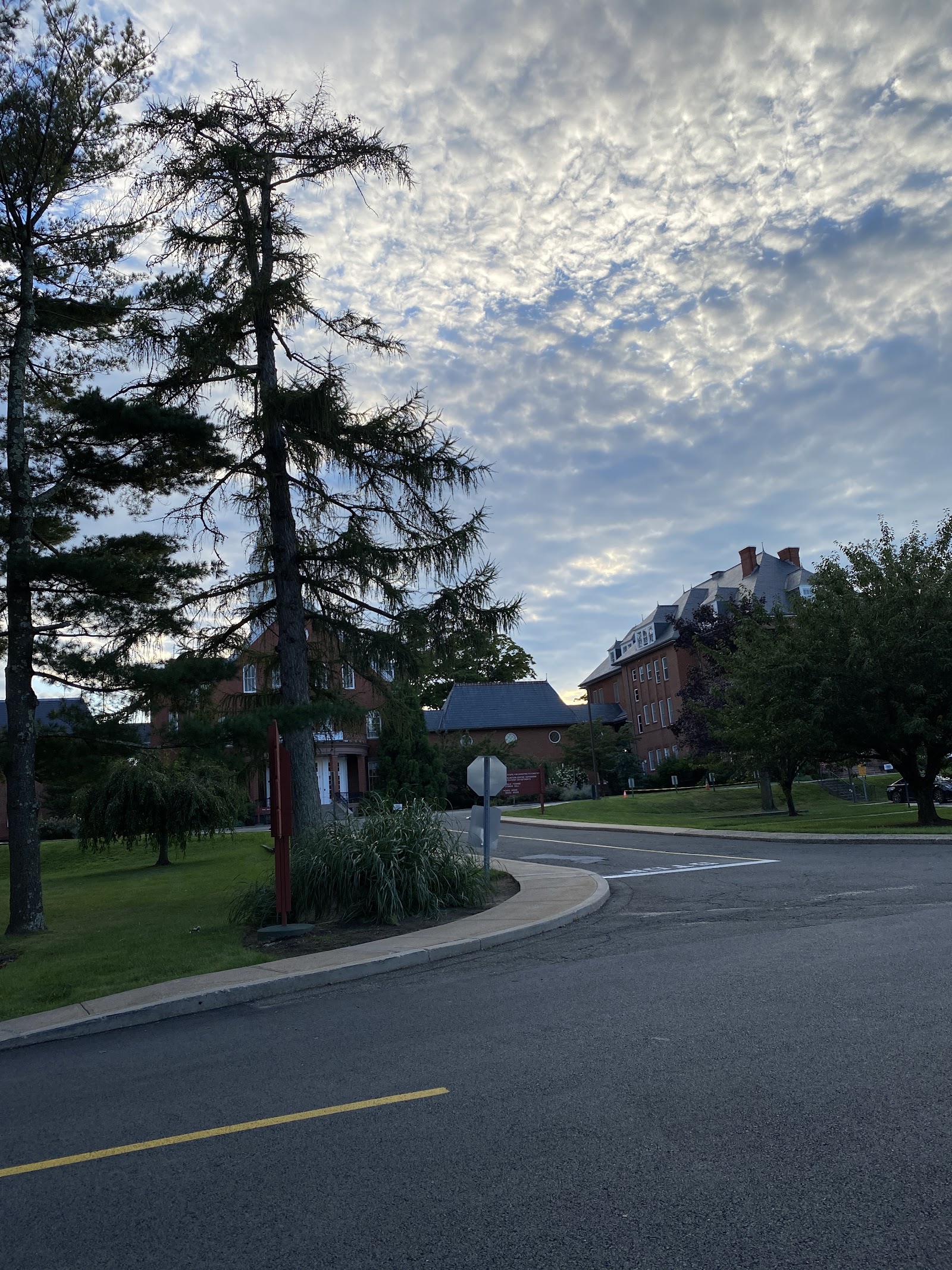 Exterior daytime view of facility entrance with parking, mature trees, and brick buildings