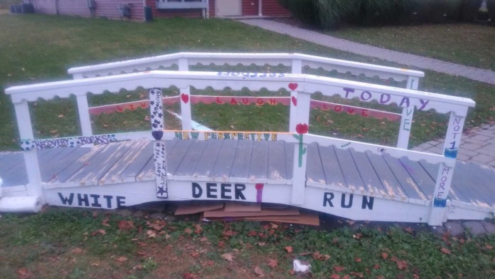 White wooden bridge decoration with heart details and White Deer Run facility branding on painted signage