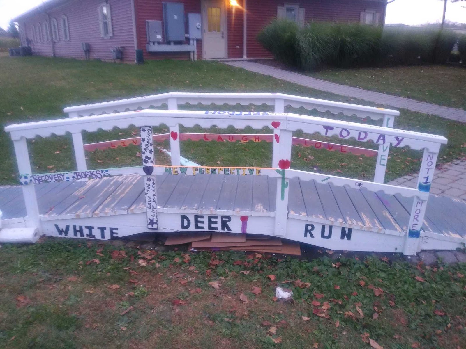 White wooden bridge decoration with heart details and White Deer Run facility branding on painted signage