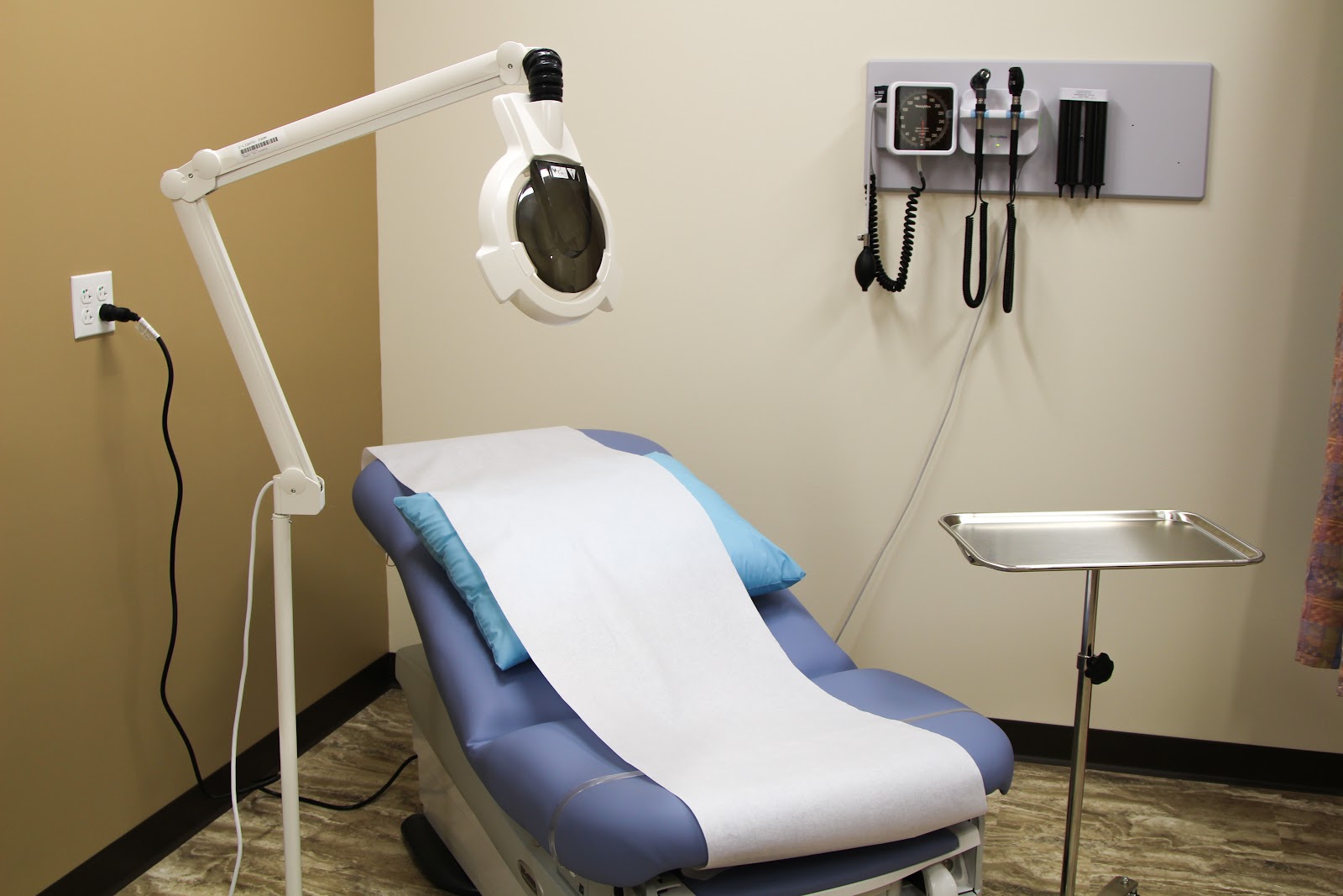 Interior dental treatment room with patient chair, overhead operatory light, and wall-mounted diagnostic equipment