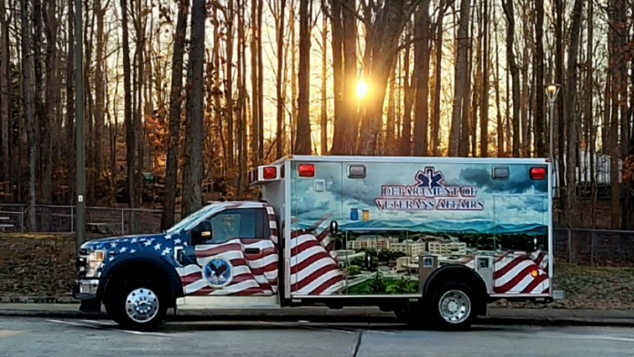 Exterior ambulance vehicle with patriotic American flag design and Department of Veterans Affairs branding parked on facility grounds