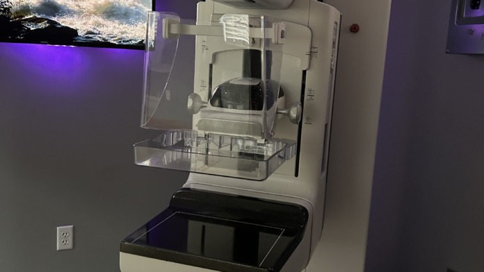 Interior diagnostic imaging room with white Hologic medical device and purple ambient lighting.