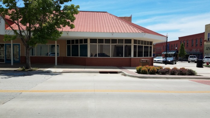 Exterior street-level view of treatment center in downtown area with large windows, brick base, metal roof, and adjacent buildings