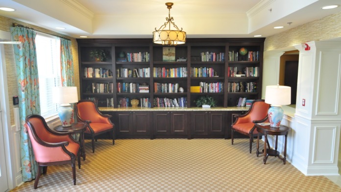 Interior lobby featuring reception window with framed artwork, decorative sconces, wainscoting, elegant furnishings, and polished floors